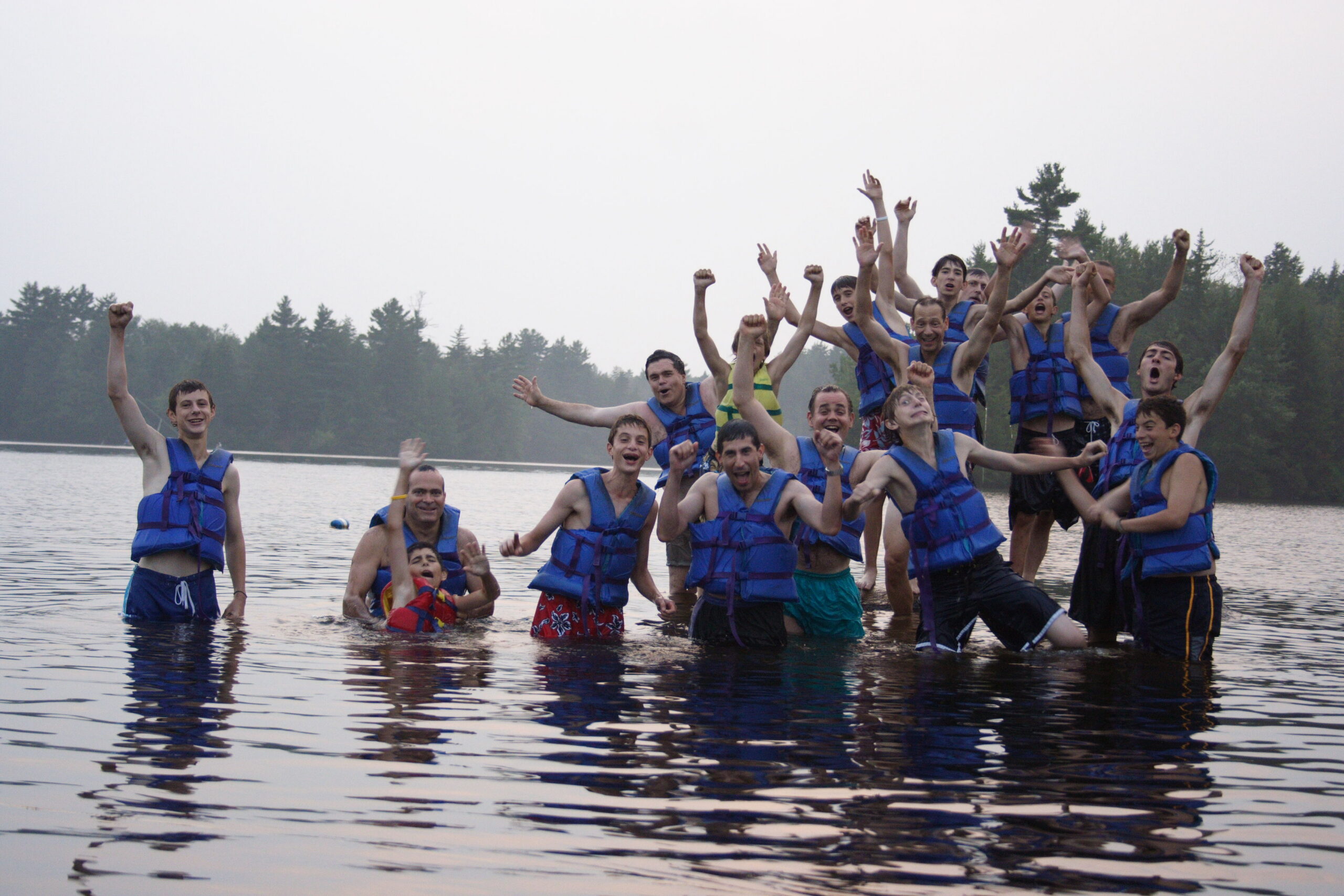 Campers playing in a lake with cloudy skies.